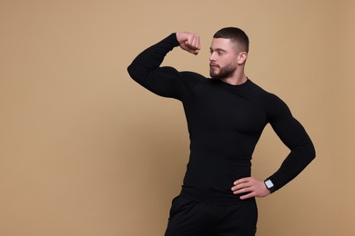 Photo of Handsome sportsman showing muscles on brown background, space for text