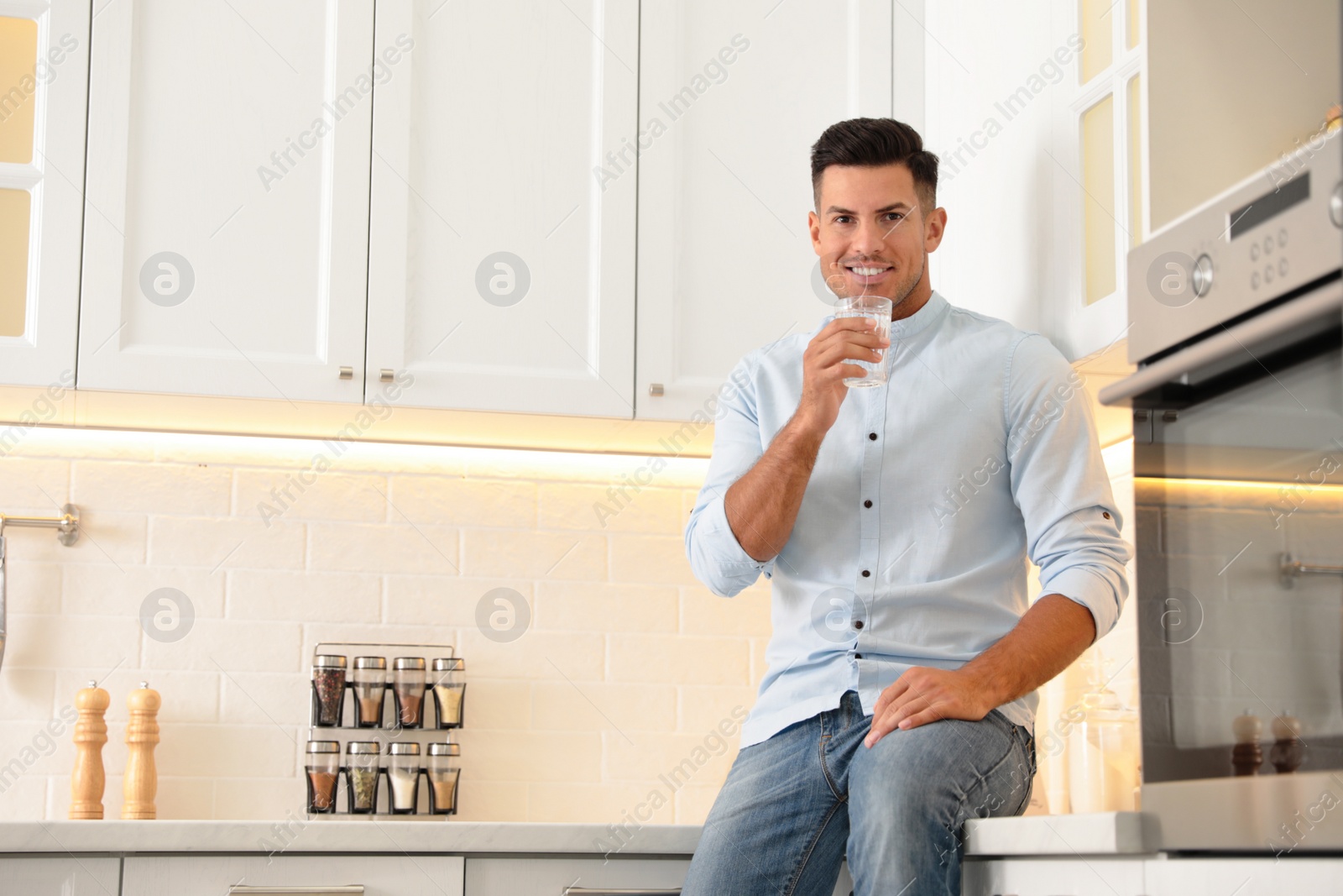 Photo of Man drinking pure water from glass in kitchen. Space for text
