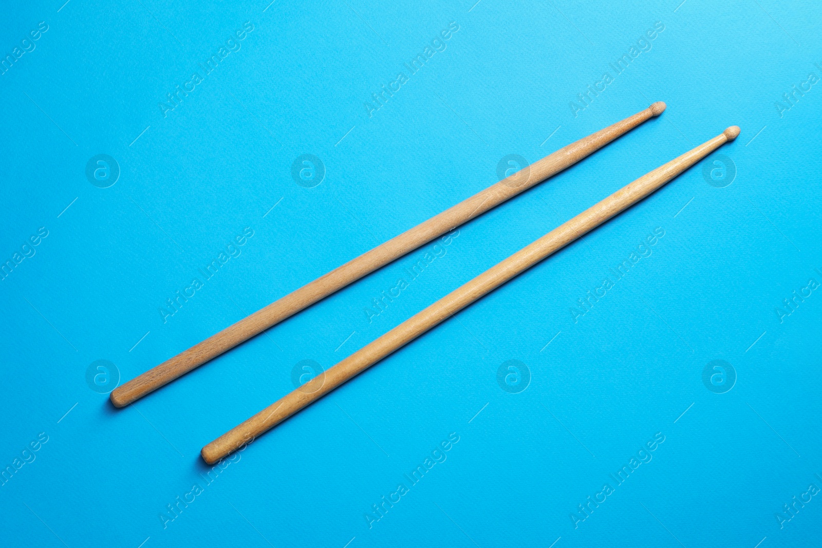 Photo of Two wooden drum sticks on light blue background