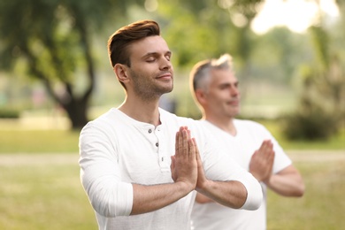 Photo of Men practicing yoga in park at morning
