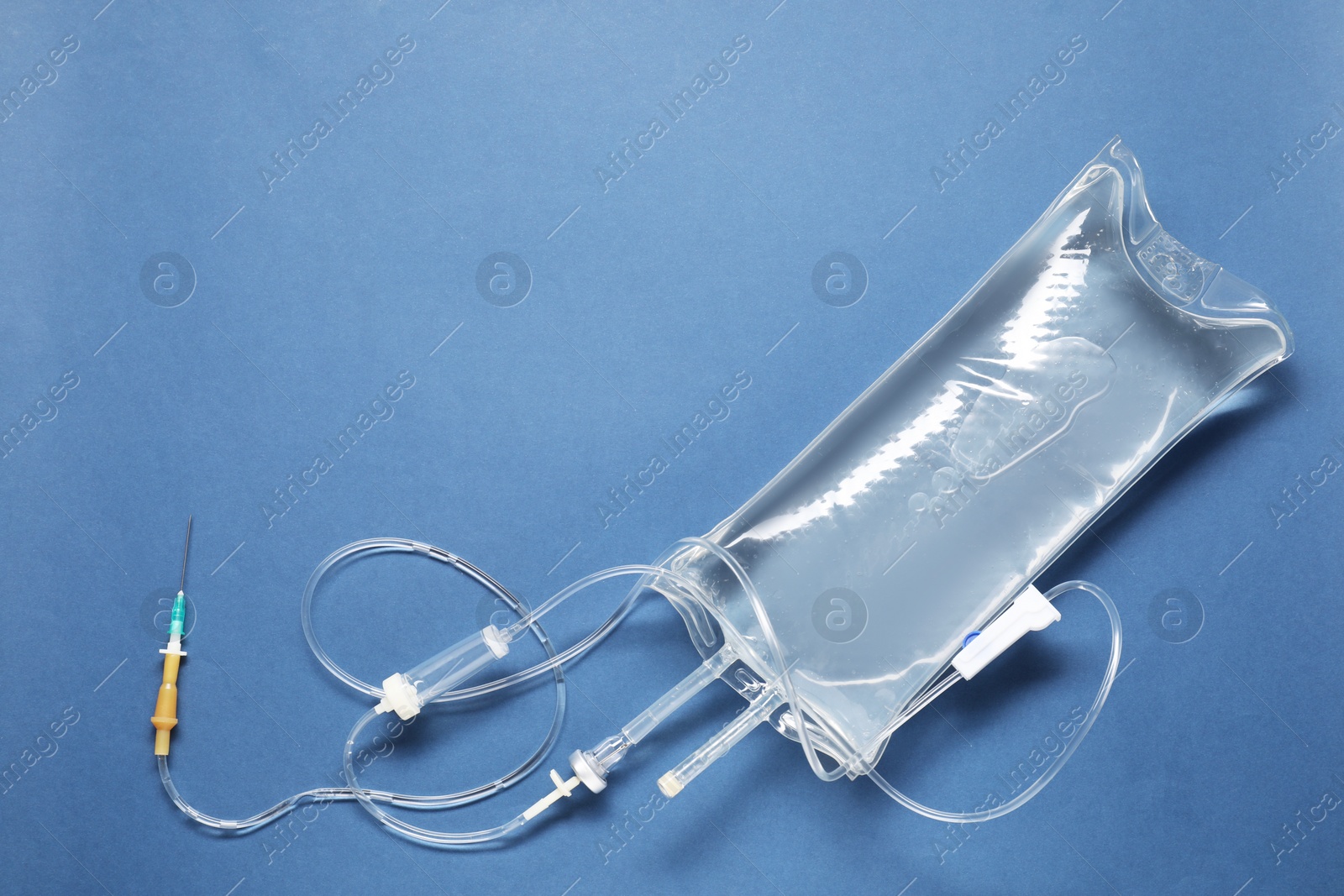 Photo of IV infusion set on blue background, top view. Space for text