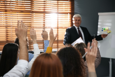 Photo of People raising hands to ask questions at seminar in office