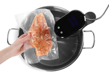 Photo of Woman putting vacuum packed meat into pot with sous vide cooker on white background, top view. Thermal immersion circulator