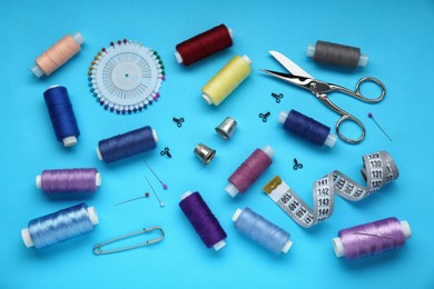 Photo of Flat lay composition with thimbles and different sewing tools on light blue background