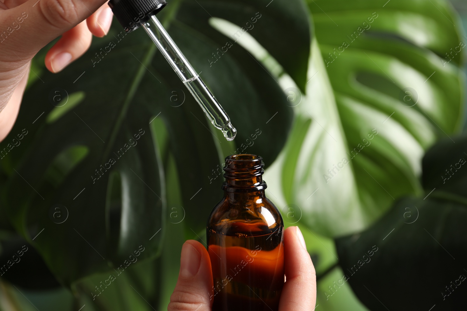 Photo of Woman with bottle of cosmetic serum and pipette on blurred background, closeup