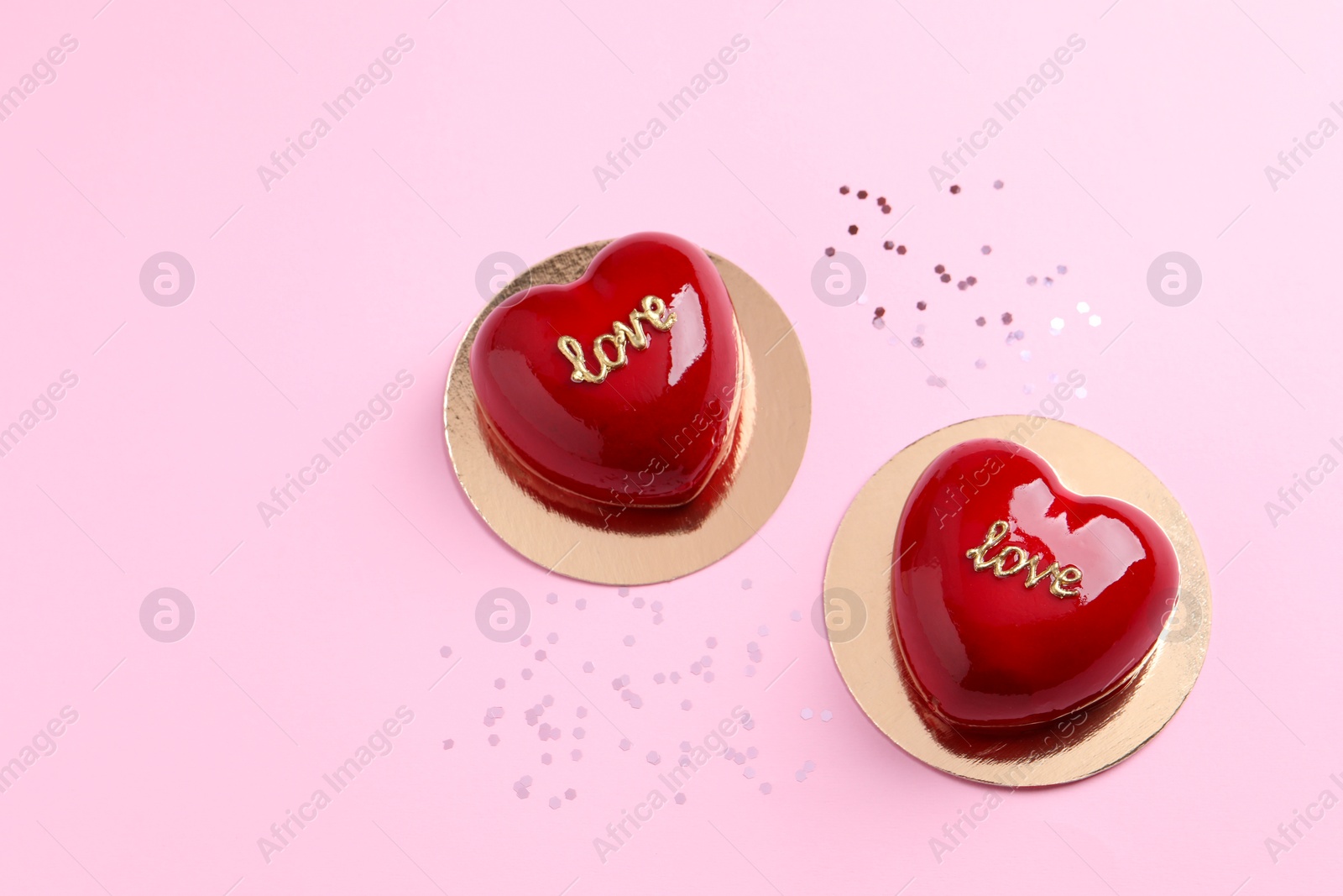 Photo of St. Valentine's Day. Delicious heart shaped cakes on light pink background, flat lay. Space for text