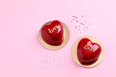 Photo of St. Valentine's Day. Delicious heart shaped cakes on light pink background, flat lay. Space for text