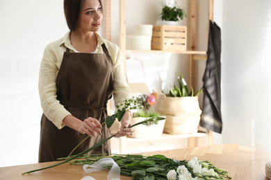 Photo of Florist making beautiful bouquet at table in workshop