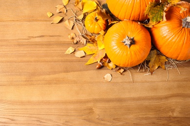 Photo of Flat lay composition with ripe pumpkins and autumn leaves on wooden table, space for text. Happy Thanksgiving day