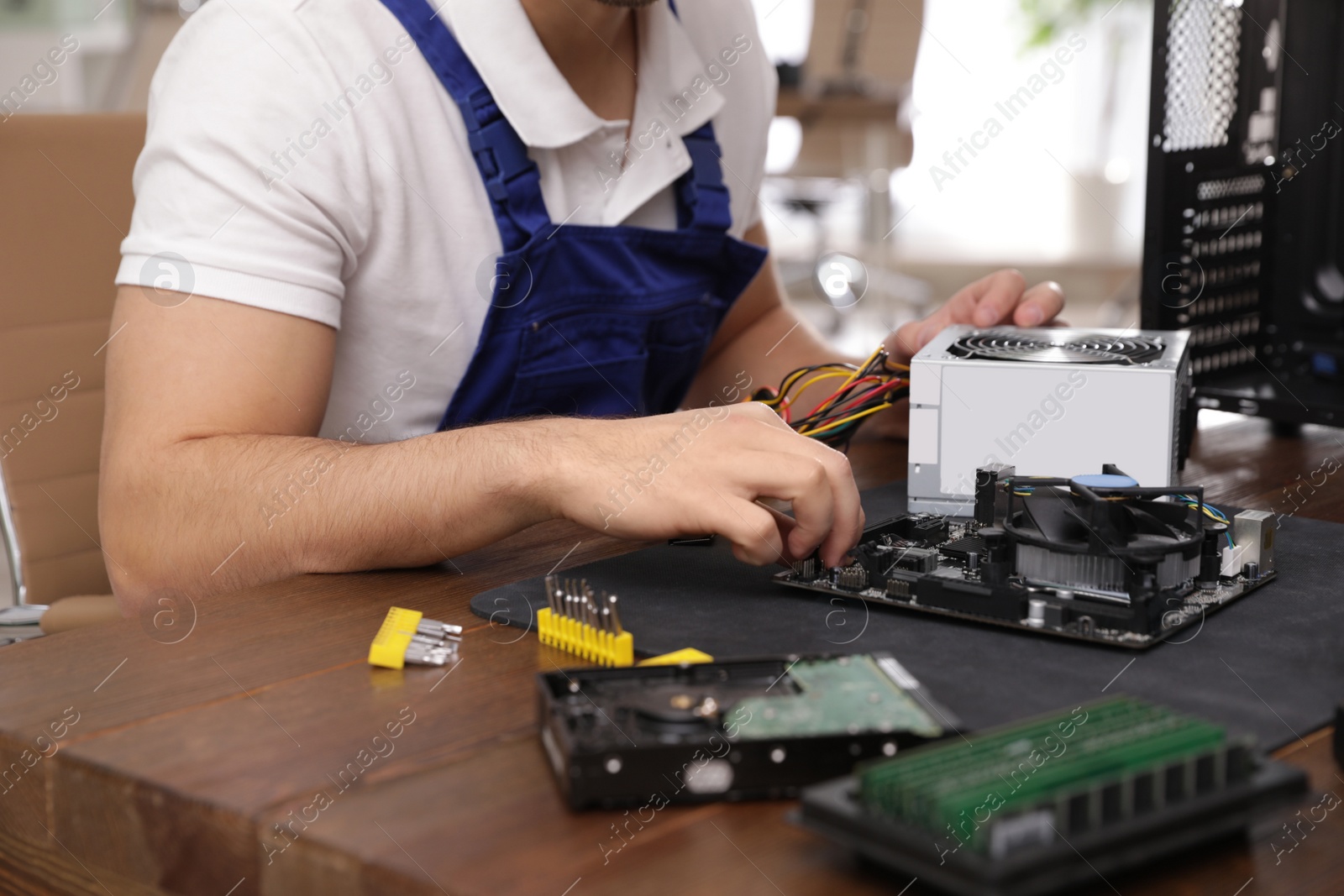 Photo of Male technician repairing computer at table indoors, closeup