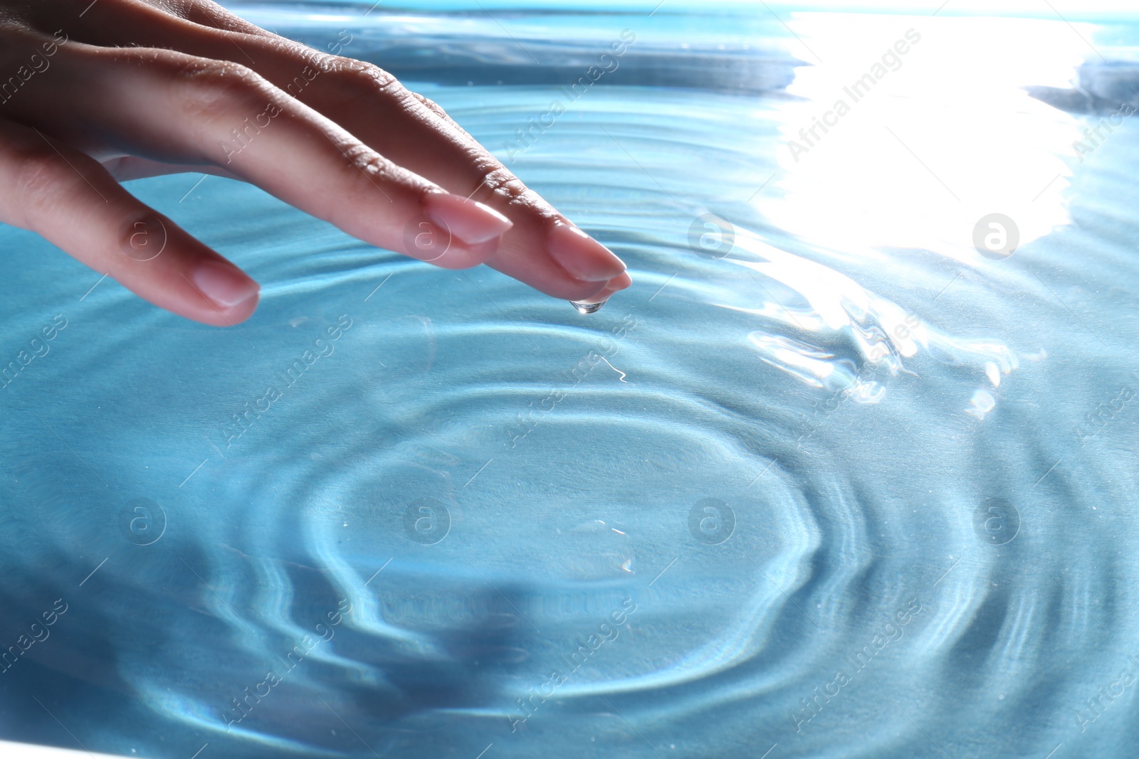 Photo of Woman touching clear water, closeup. Making ripples