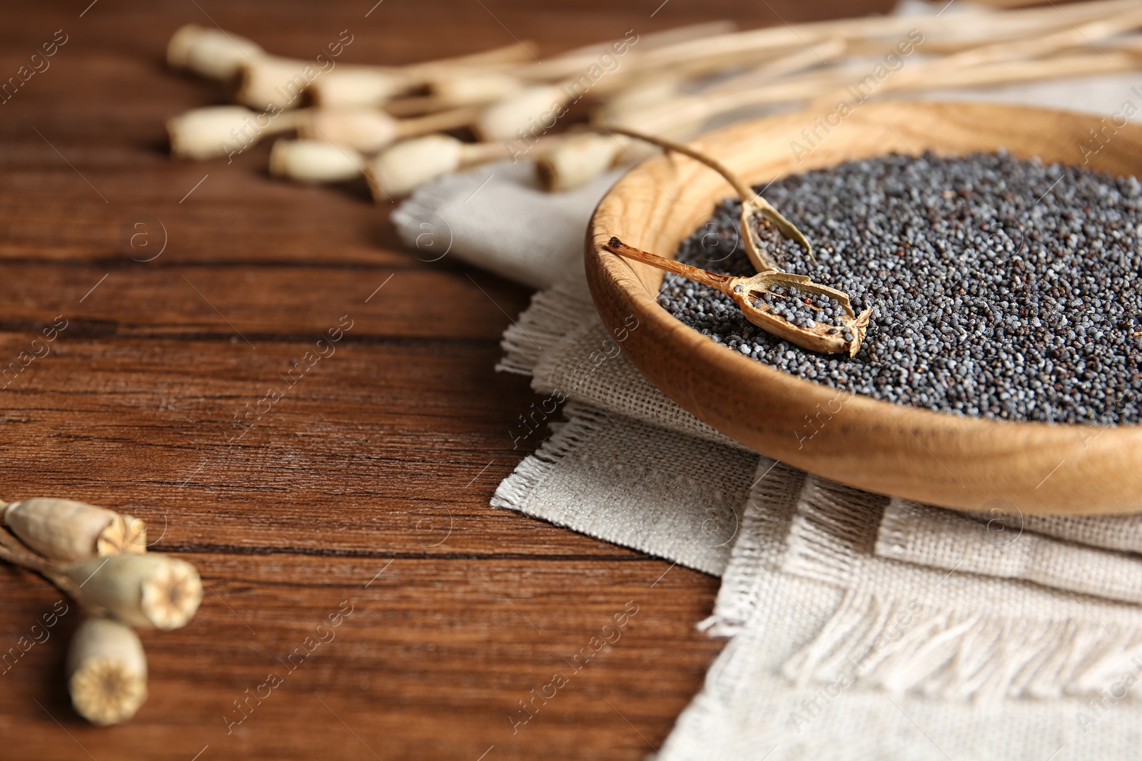 Photo of Plate with poppy seeds on wooden table