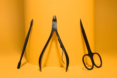 Manicure scissors, cuticle nipper and pusher on yellow background
