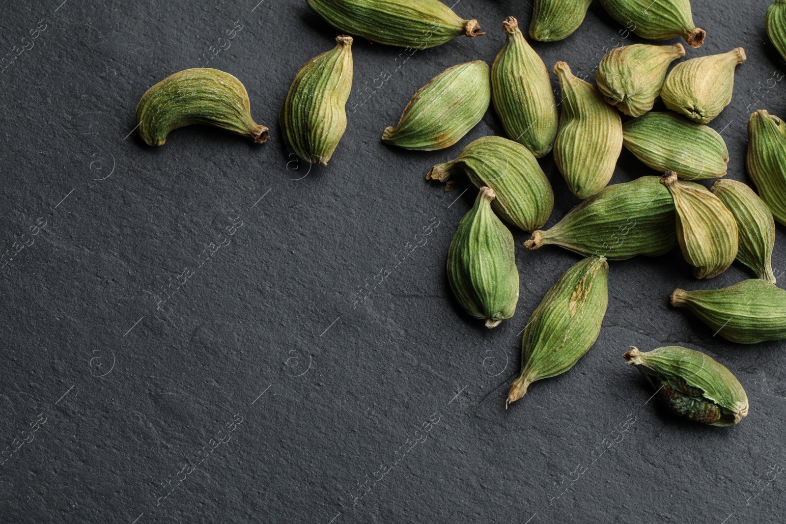Photo of Dry cardamom pods on black table, top view. Space for text