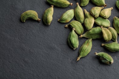 Photo of Dry cardamom pods on black table, top view. Space for text