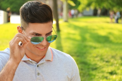 Photo of Handsome man wearing stylish sunglasses in park. Space for text