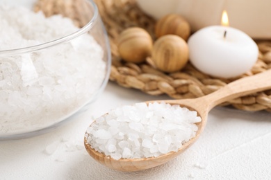 Wooden spoon with sea salt for spa scrubbing procedure on white table, closeup