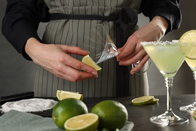 Woman making delicious Margarita cocktail at grey table, closeup