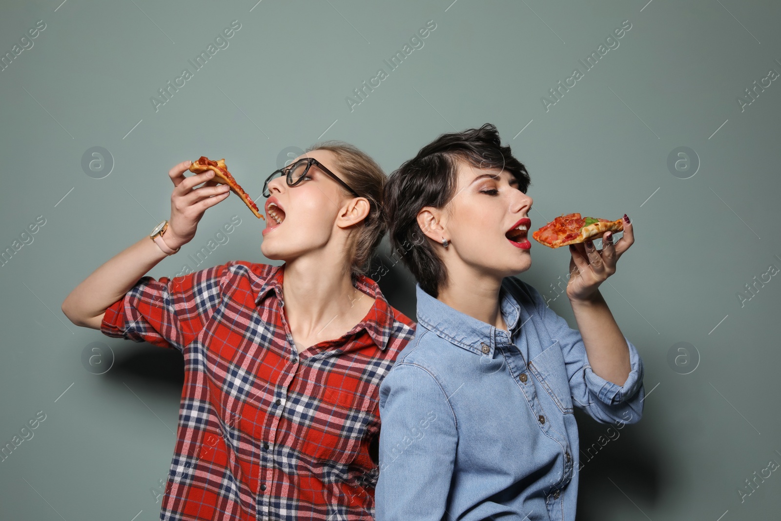 Photo of Attractive young women with slices of delicious pizza on color background