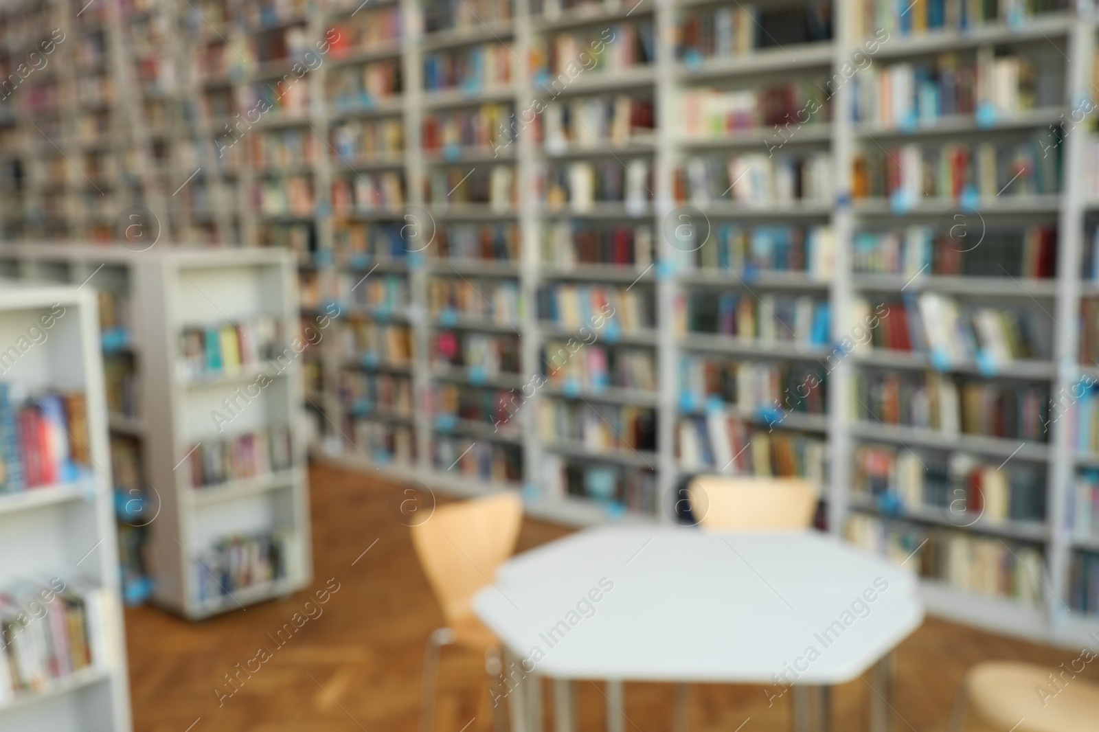 Photo of Blurred view of bookshelves and table in library