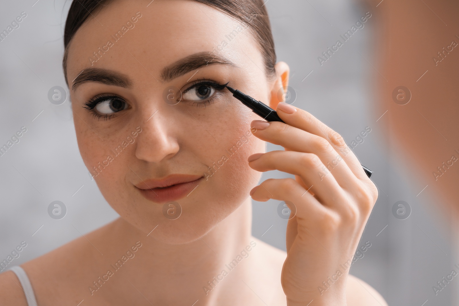 Photo of Makeup product. Woman applying black eyeliner indoors, closeup