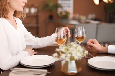 Photo of Young couple with glasses of delicious wine in restaurant