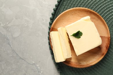 Photo of Cut tasty butter with parsley on grey table, top view. Space for text