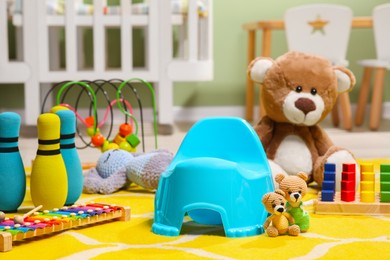 Photo of Light blue baby potty, teddy bear and many other toys in room. Toilet training