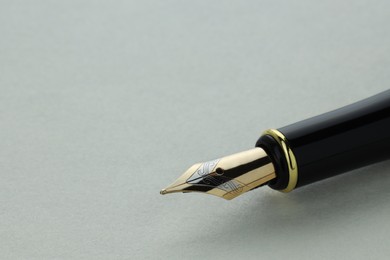 Photo of Stylish fountain pen on light grey table, closeup. Space for text