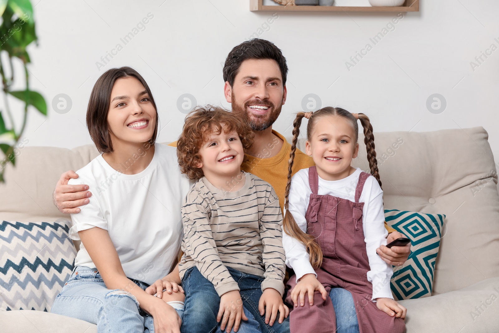 Photo of Happy family watching TV on sofa indoors