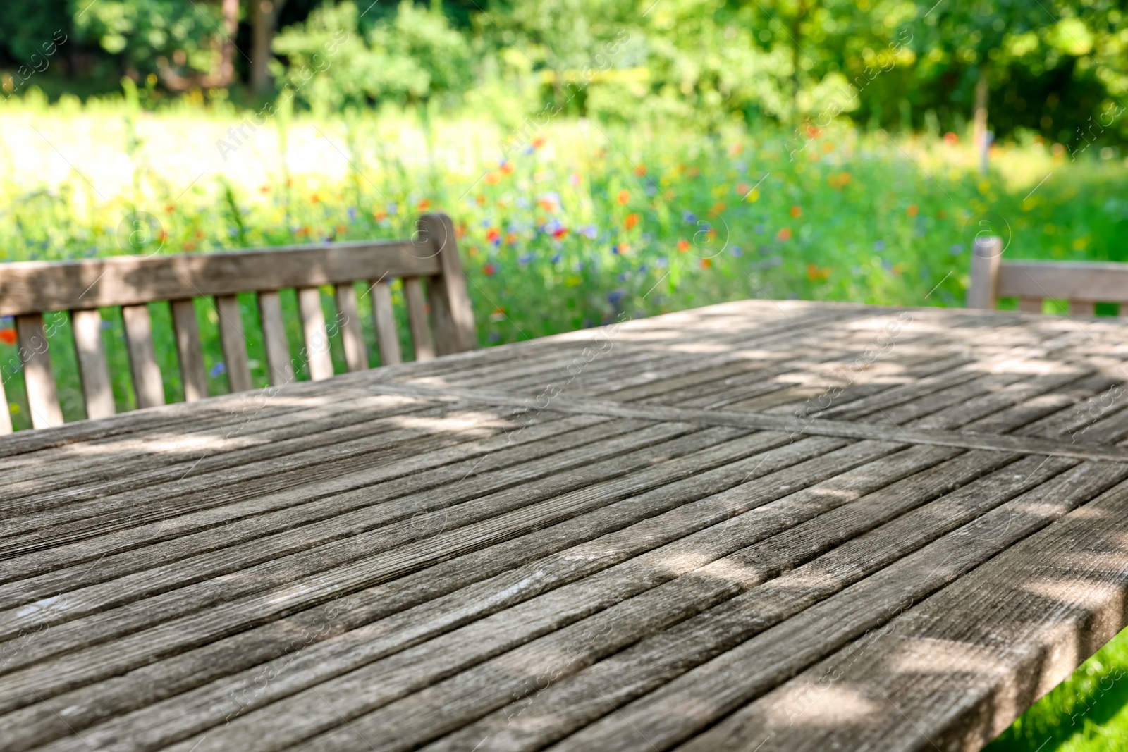 Photo of Empty wooden table with bench on sunny day in garden