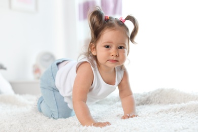 Photo of Adorable little baby girl crawling on bed in room
