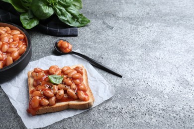 Photo of Toast with delicious canned beans on grey table, space for text