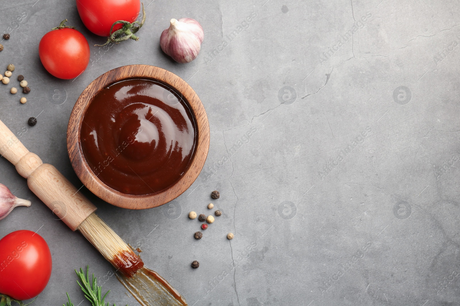 Photo of Flat lay composition with tasty barbeque sauce in bowl on grey textured table. Space for text