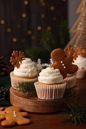 Photo of Different beautiful Christmas cupcakes and fir branches on wooden table. Space for text