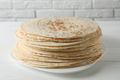 Photo of Stack of tasty homemade tortillas on white wooden table