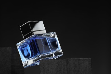 Luxury men`s perfume in bottle against dark background, space for text