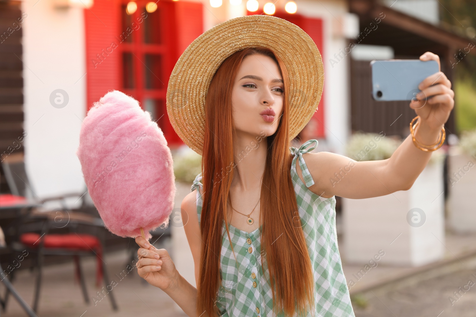 Photo of Funny woman with cotton candy taking selfie outdoors