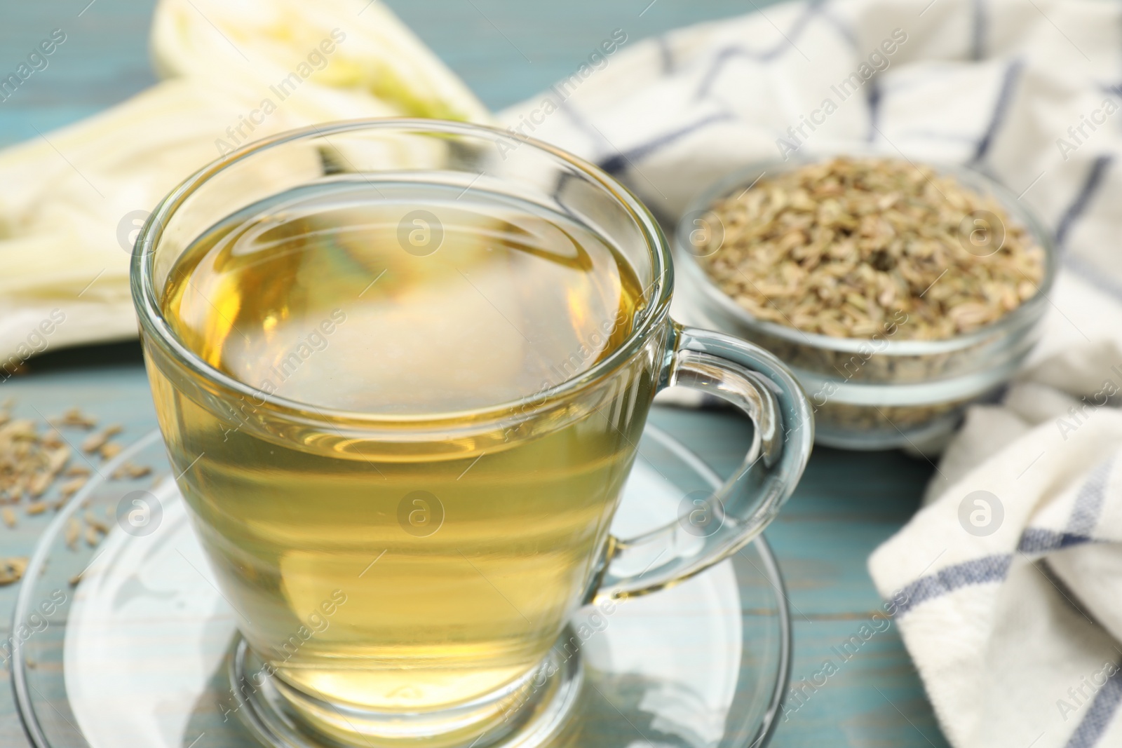 Photo of Aromatic fennel tea in cup on light blue wooden table, closeup