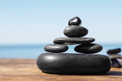 Photo of Stack of stones on wooden pier near sea, space for text. Zen concept