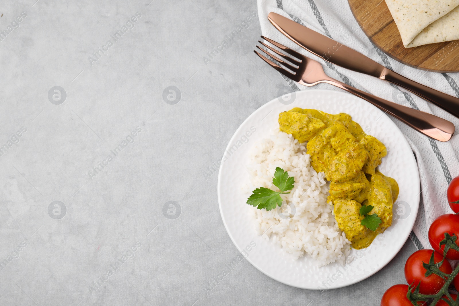 Photo of Delicious rice, chicken with curry sauce and tomatoes on light grey table, flat lay. Space for text