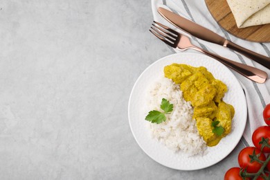 Photo of Delicious rice, chicken with curry sauce and tomatoes on light grey table, flat lay. Space for text