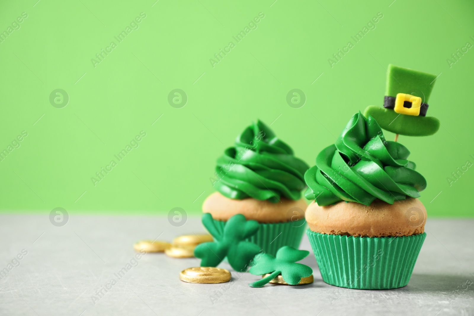 Photo of Decorated cupcakes and coins on grey table, space for text. St. Patrick's Day celebration