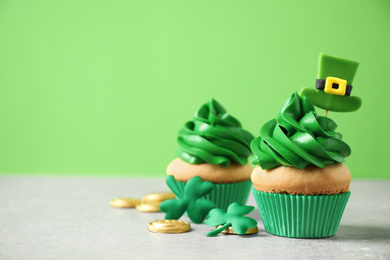 Decorated cupcakes and coins on grey table, space for text. St. Patrick's Day celebration