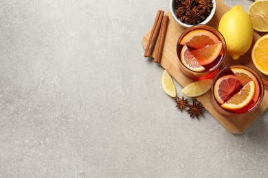 Photo of Aromatic punch drink and ingredients on light grey table, flat lay. Space for text