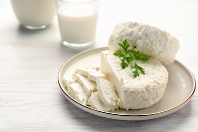 Photo of Delicious fresh cottage cheese with parsley on white wooden table