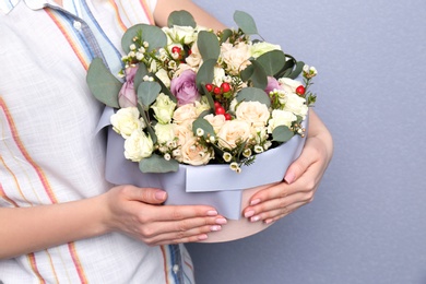 Photo of Female florist holding box with flowers on grey background