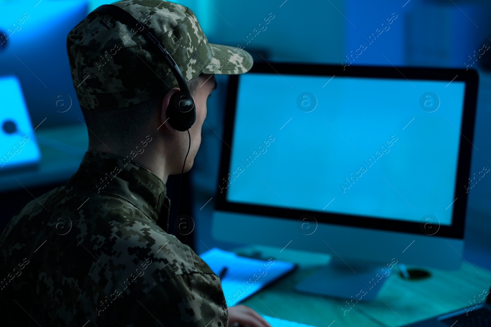 Image of Military service. Soldier in headphones working at table in office at night