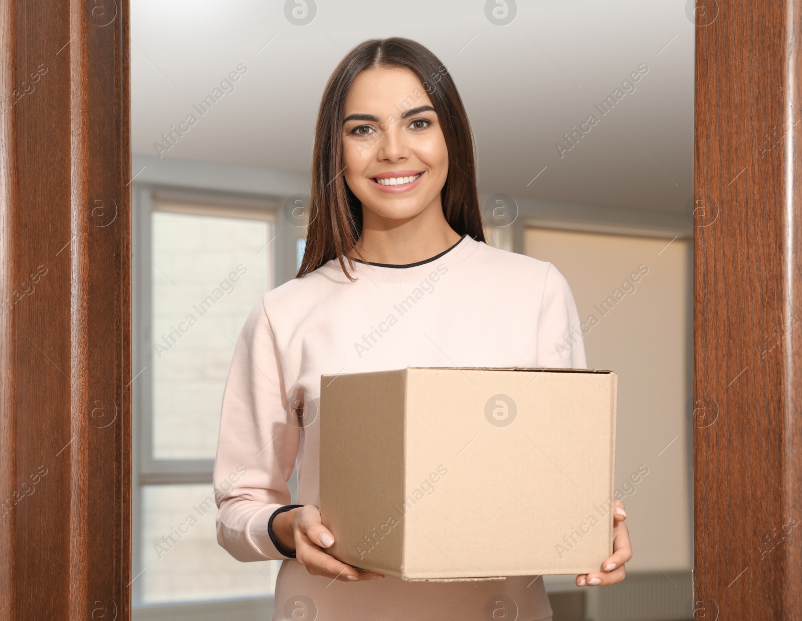 Photo of Portrait of smiling woman with parcel at door, mockup for design. Delivery service