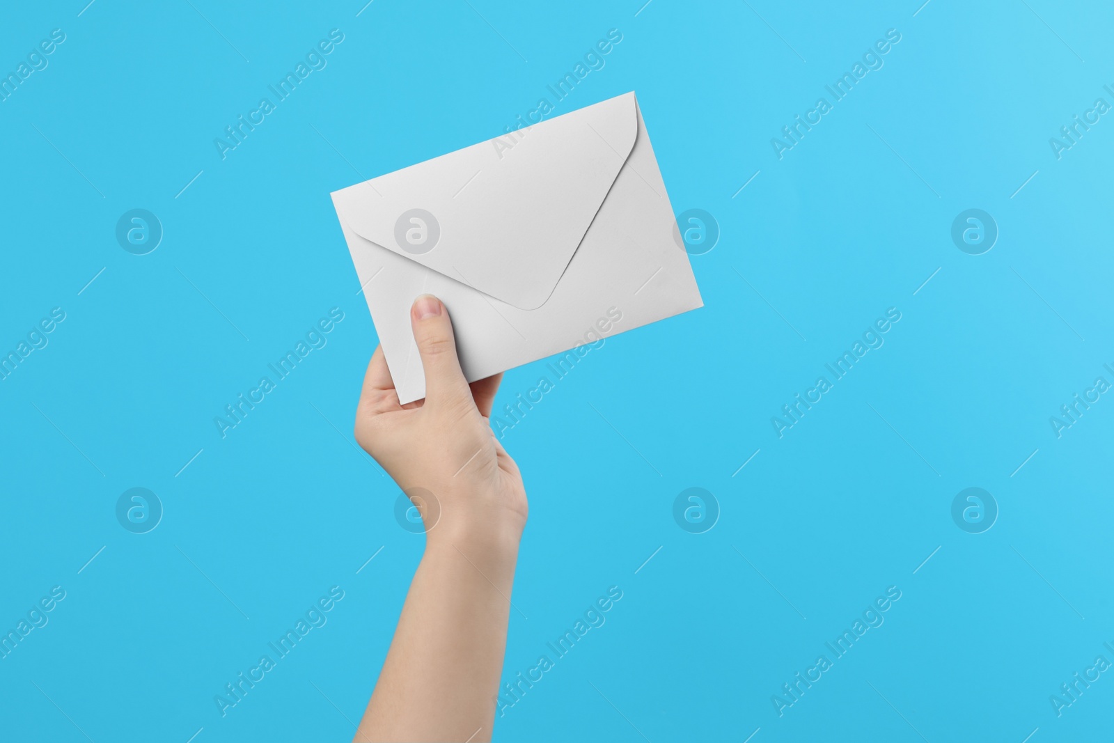 Photo of Woman holding white paper envelope on light blue background, closeup